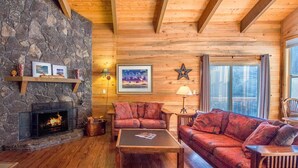 L’intérieur d’un chalet confortable, avec une cheminée en pierre, des murs en bois et une grande fenêtre.
