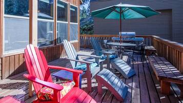 Una terraza con sillas Adirondack, una mesa y una parrilla.