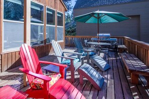 A deck with Adirondack chairs, a table, and a grill. - Mink 3 (Bend)
