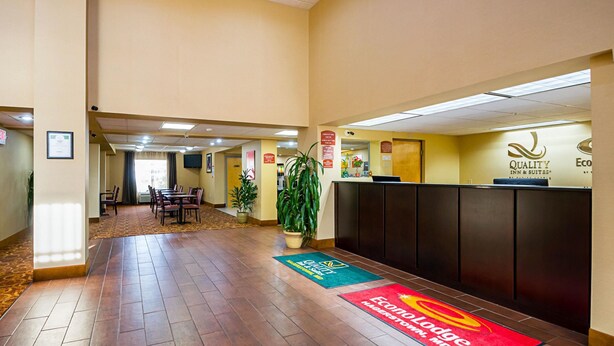 Een hotel receptie met een receptiebalie, een wachtruimte met stoelen, en een kamerplant.
