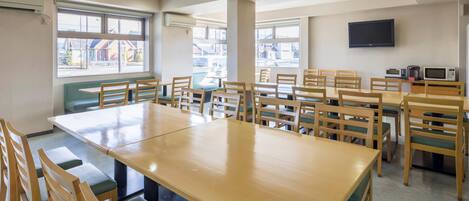 A conference room with a large table and chairs, air conditioning units, and a television on the wall.