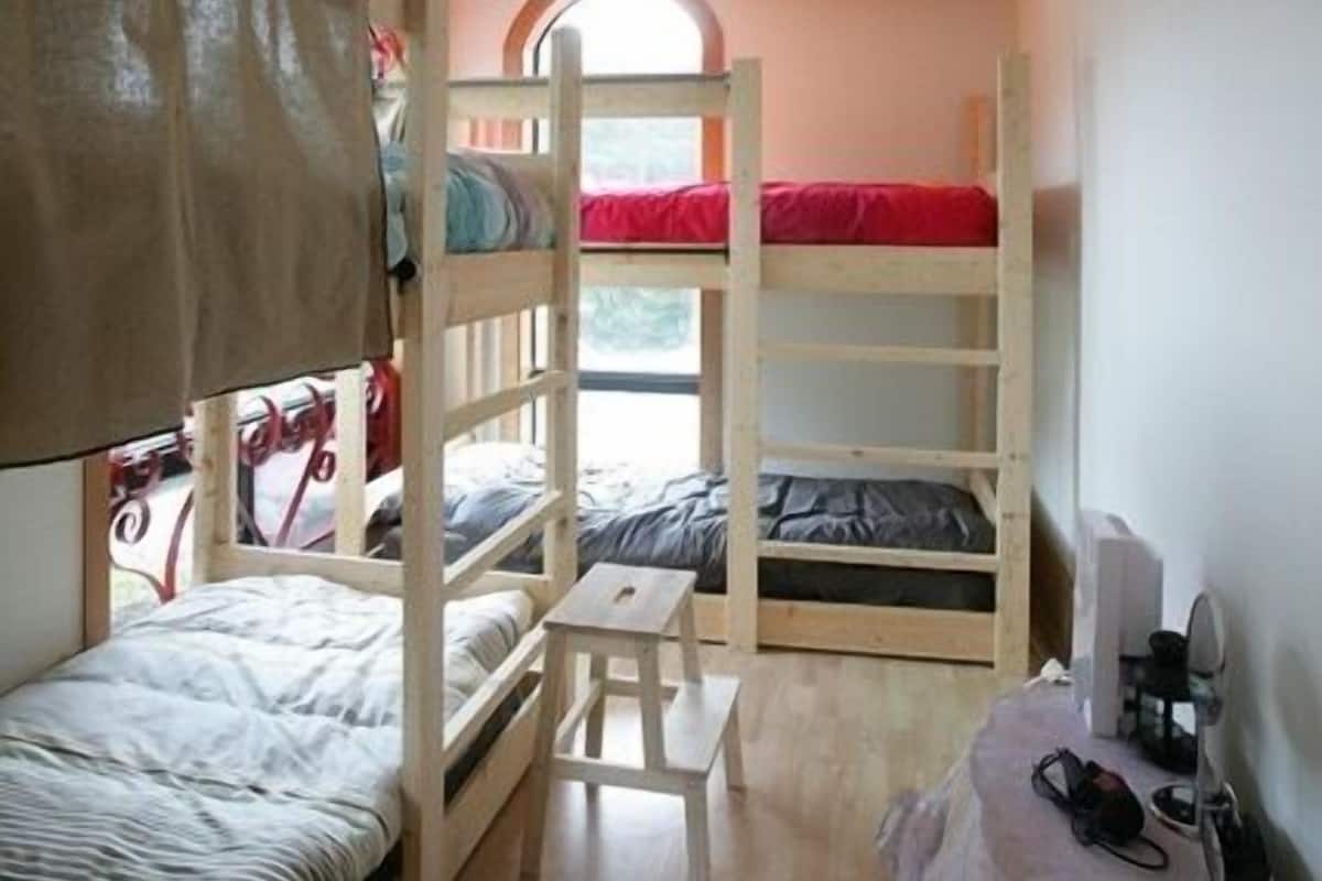 Une petite pièce avec des lits superposés, une petite table et une fenêtre.