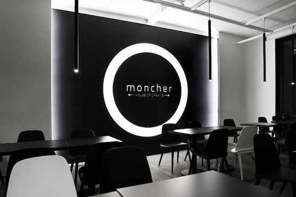 A modern conference room with a black and white color scheme, featuring a prominent circular logo on the wall and several tables and chairs arranged for meetings.