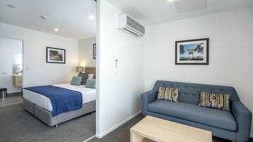 Una habitación de hotel moderna con una cama, un sofá, una mesa de centro y un cuadro en la pared.