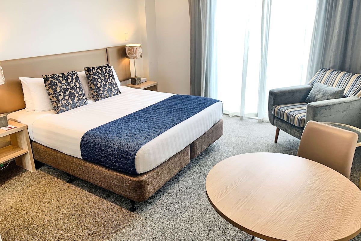 Ein Hotelzimmer mit einem Bett, einem runden Tisch, einem Stuhl und einer Lampe.