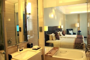 A hotel bathroom with a large mirror, a sink, a bathtub, and a bed with a headboard. - ZTE Hotel Xi'an (Xi'an)