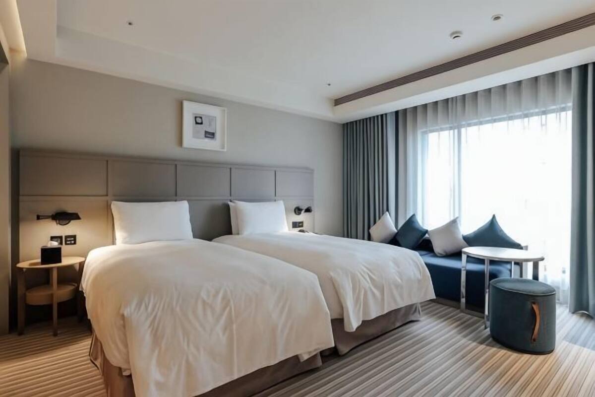 A hotel room with a large bed, bedside tables, a sofa, and a small table.