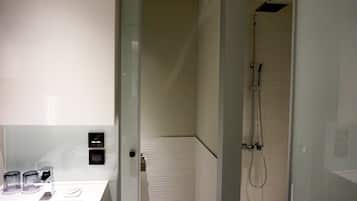 Une salle de bain moderne avec une douche à parois de verre, des murs recouverts de carreaux blancs et un design minimaliste.