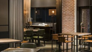 A modern dining area with brick walls, green upholstered chairs, and a bar area with stools. - Greet Inn (Kaohsiung)