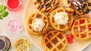 Een bord met wafels, diverse toppings en sprinkles.