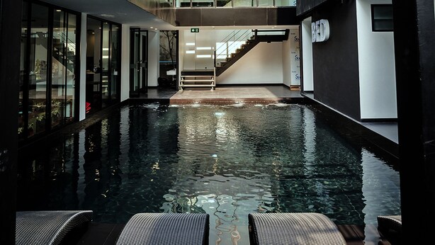 A modern building with a central pool, glass railings, and a staircase leading to upper floors.