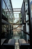 A modern building with a central pool, glass railings, and a staircase leading to upper floors.
