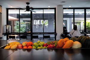 A fruit display on a table in a modern interior with large windows and a ceiling fan.