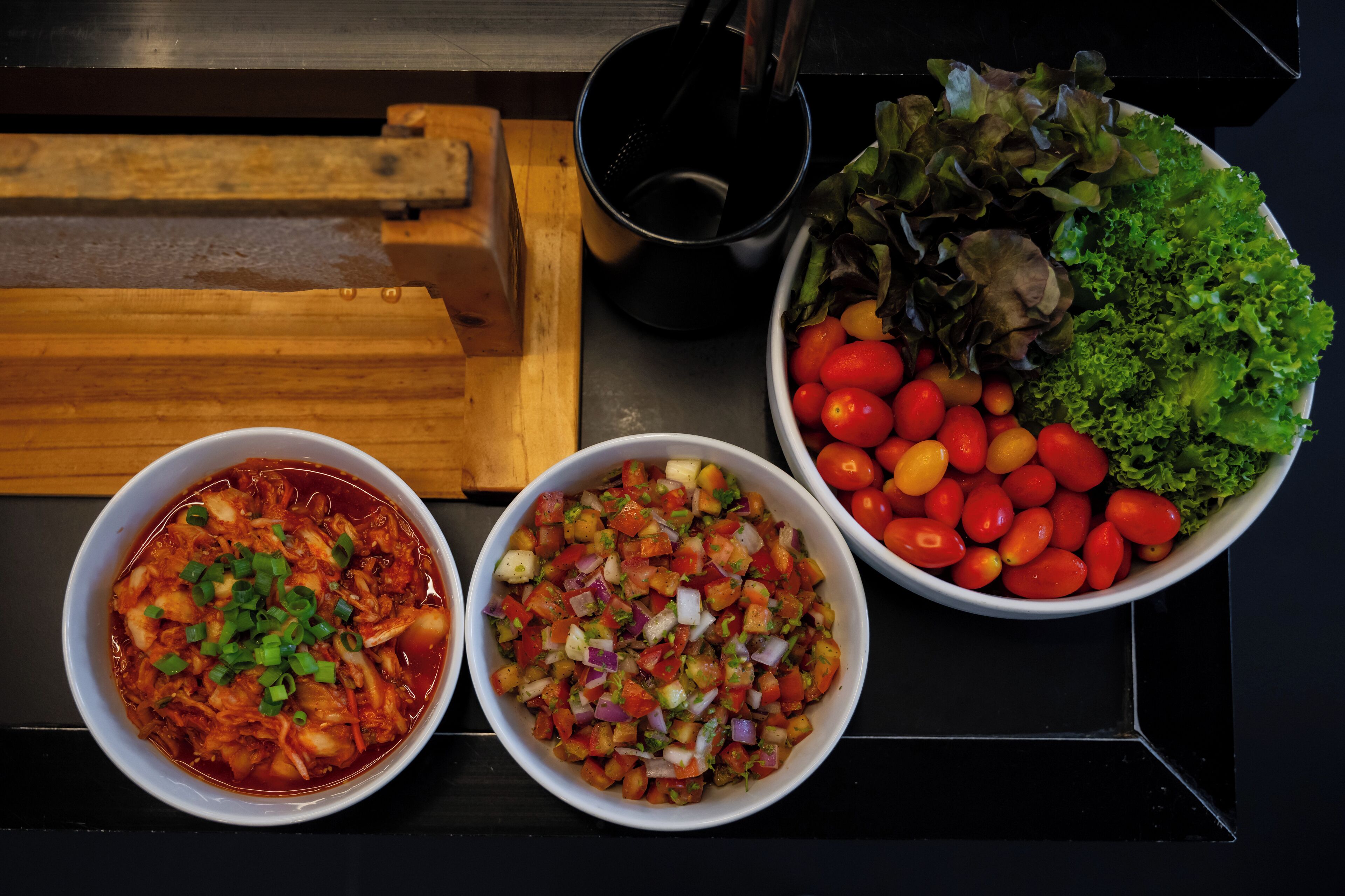 Three bowls of food on a table.