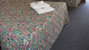 Una habitación de hotel con dos camas, un espejo, una mesita de noche y una ventana con cortinas.