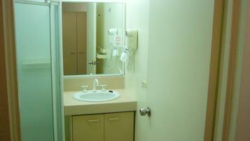 A small bathroom with a white sink, a mirror, and a hairdryer on the wall.