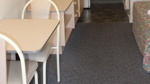 Una habitación compacta con cama, escritorio, silla, mesita y espejo.