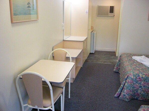 A small, compact room with a single bed, a desk, and a chair. - Mid Coast Motor Inn (Macksville)