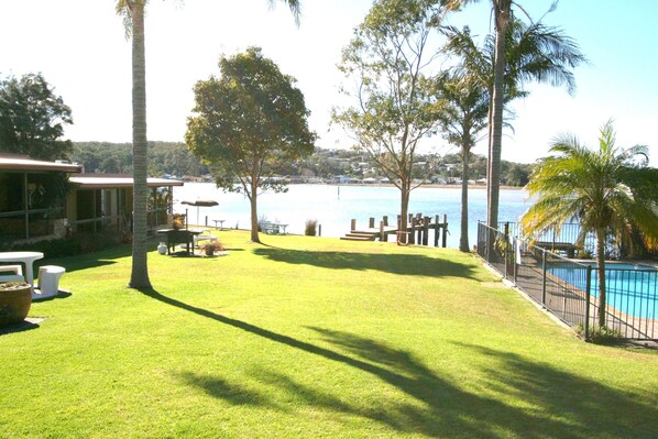 A backyard with a pool, a table, and chairs. - Lake Edge Holiday Units (Burrill Lake)