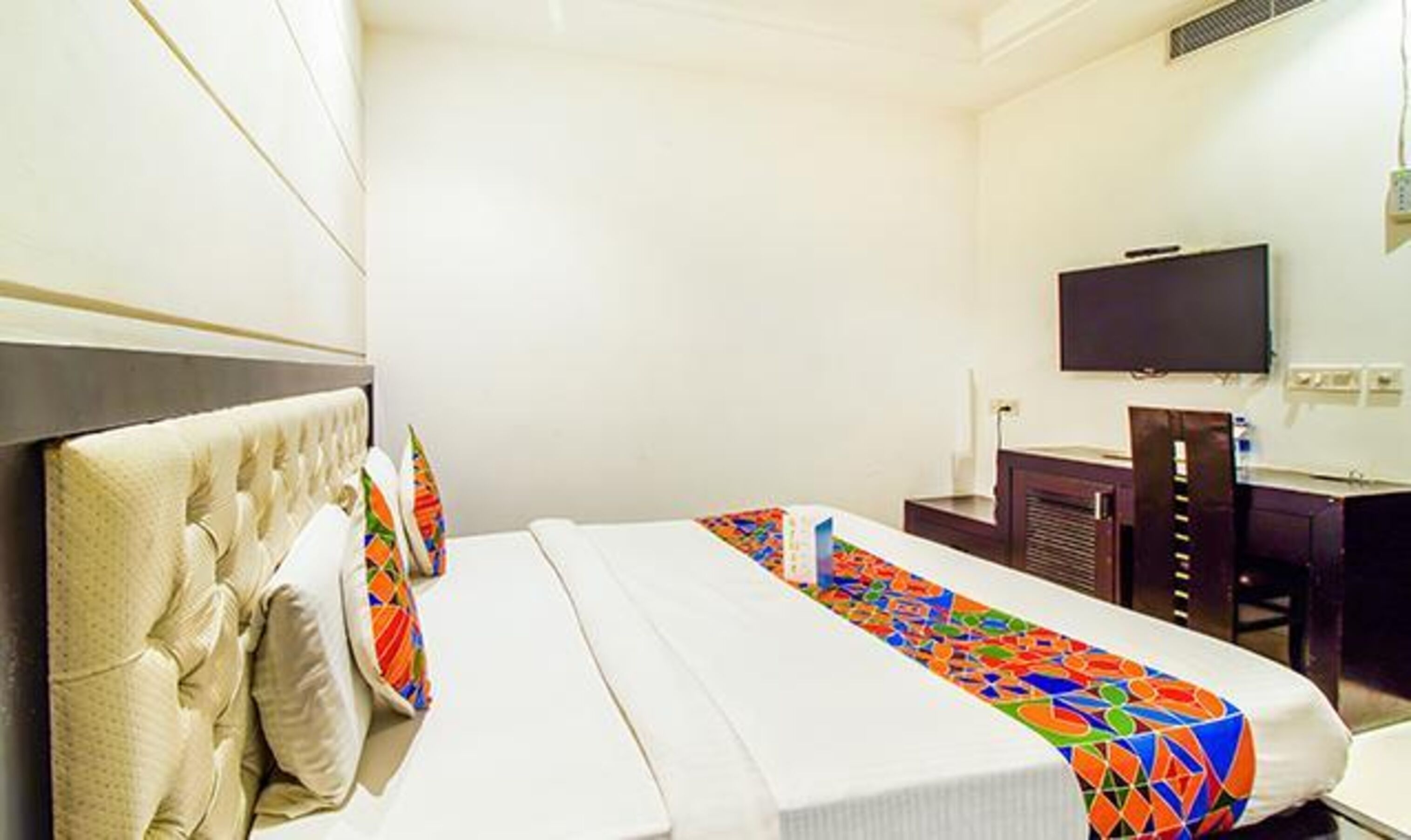 A hotel room with a bed, a desk, a television, and a window.