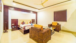 A modern hotel room with a large bed, a sofa, a coffee table, and a TV.