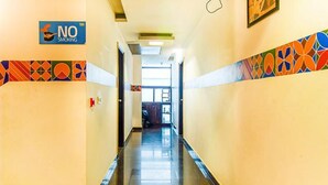 A hotel corridor with a 'NO Smoking' sign, patterned wall tiles, and a clear view to the end of the hallway.