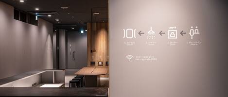 A modern hotel lobby with a reception desk, a wooden reception counter, and a wall with directional signs and Wi-Fi details.