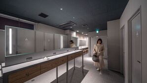 A modern bathroom with a long vanity, multiple mirrors, and a clean, minimalist design. - Capsule Plus Yokohama Sauna & Capsule (Yokohama)