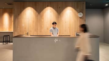 A reception desk with a wooden panel backdrop, a clock, and a sign indicating a staff-only area.