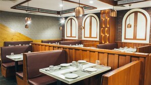 A restaurant with booth seating, wooden tables, and pendant lighting.