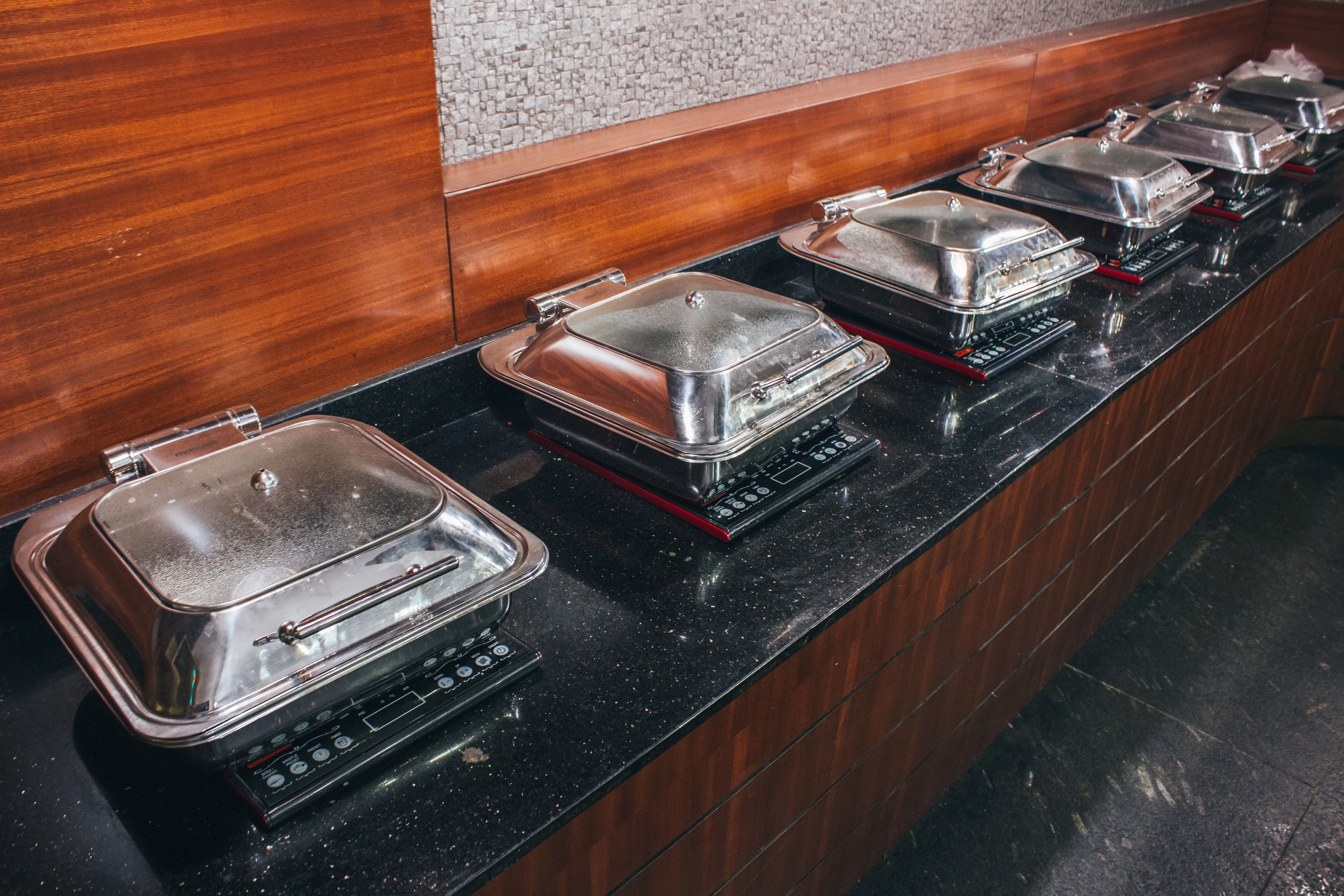 Un buffet composé de plusieurs stations en libre-service, chacune étant dotée d’un plat de service couvert et d’un panneau de commande.