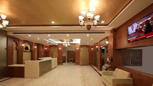 A lobby with a reception desk, seating area, and a TV screen.