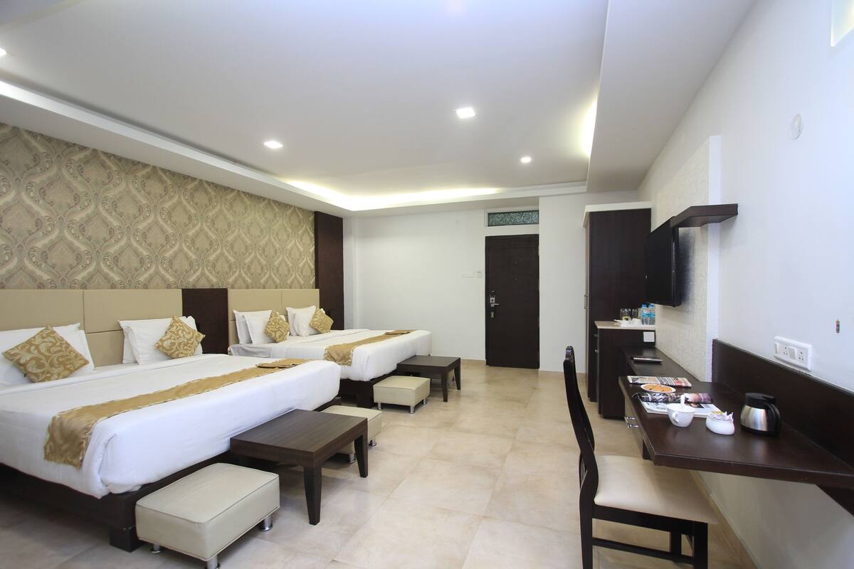 A hotel room with two beds, a desk, and a television.
