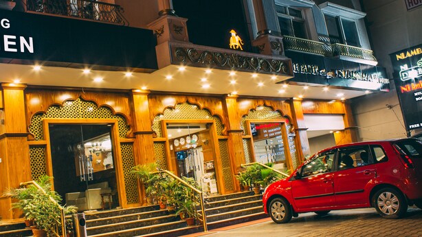 A building with a sign reading "The Veg Kitchen" and a red car parked in front.