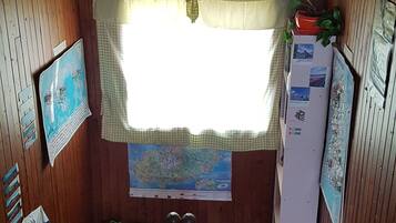 A wooden-paneled room with a window, a map on the wall, a refrigerator, and a fire extinguisher.