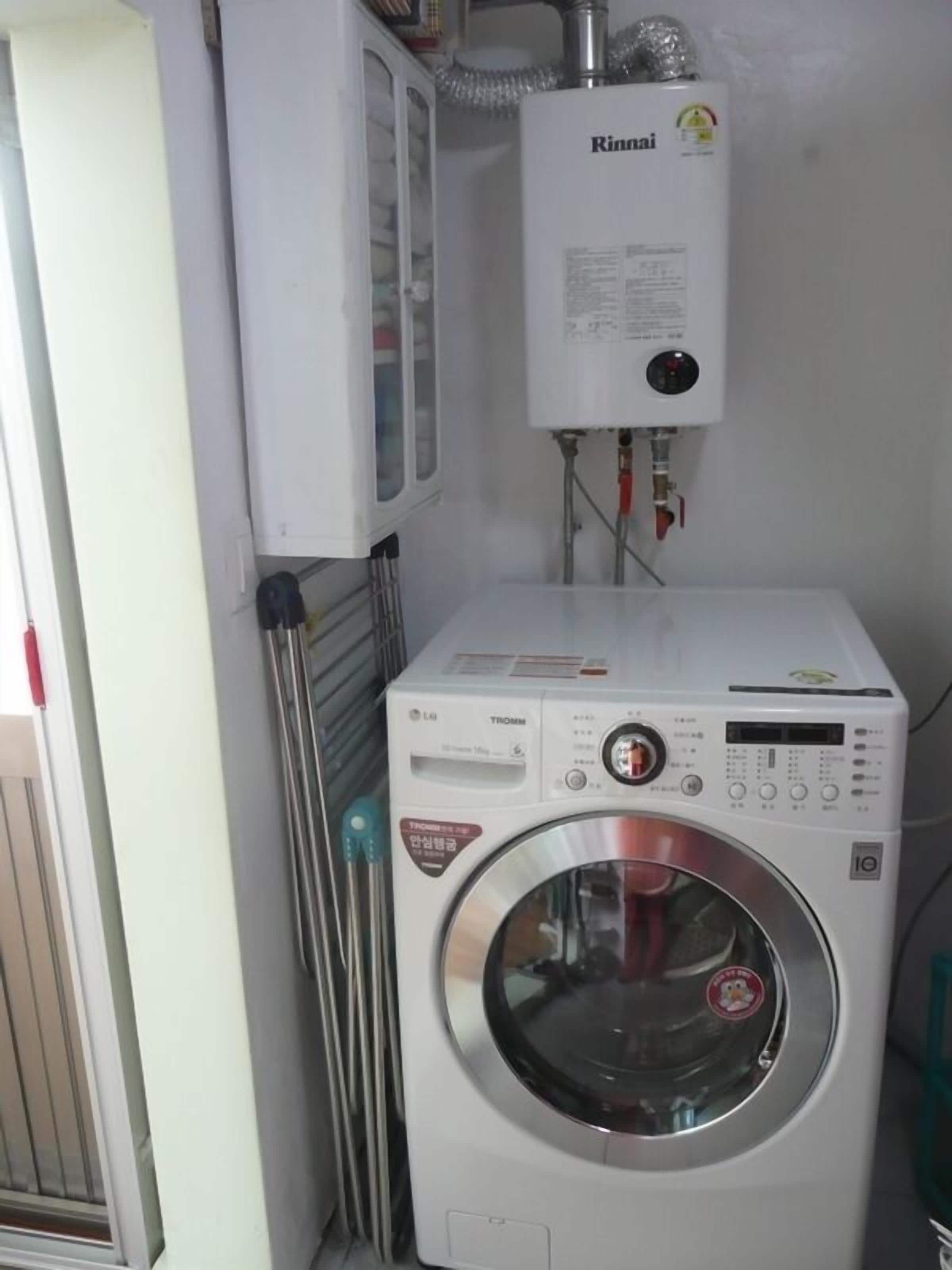Un espace buanderie équipé d’un lave-linge et d’un chauffe-eau.