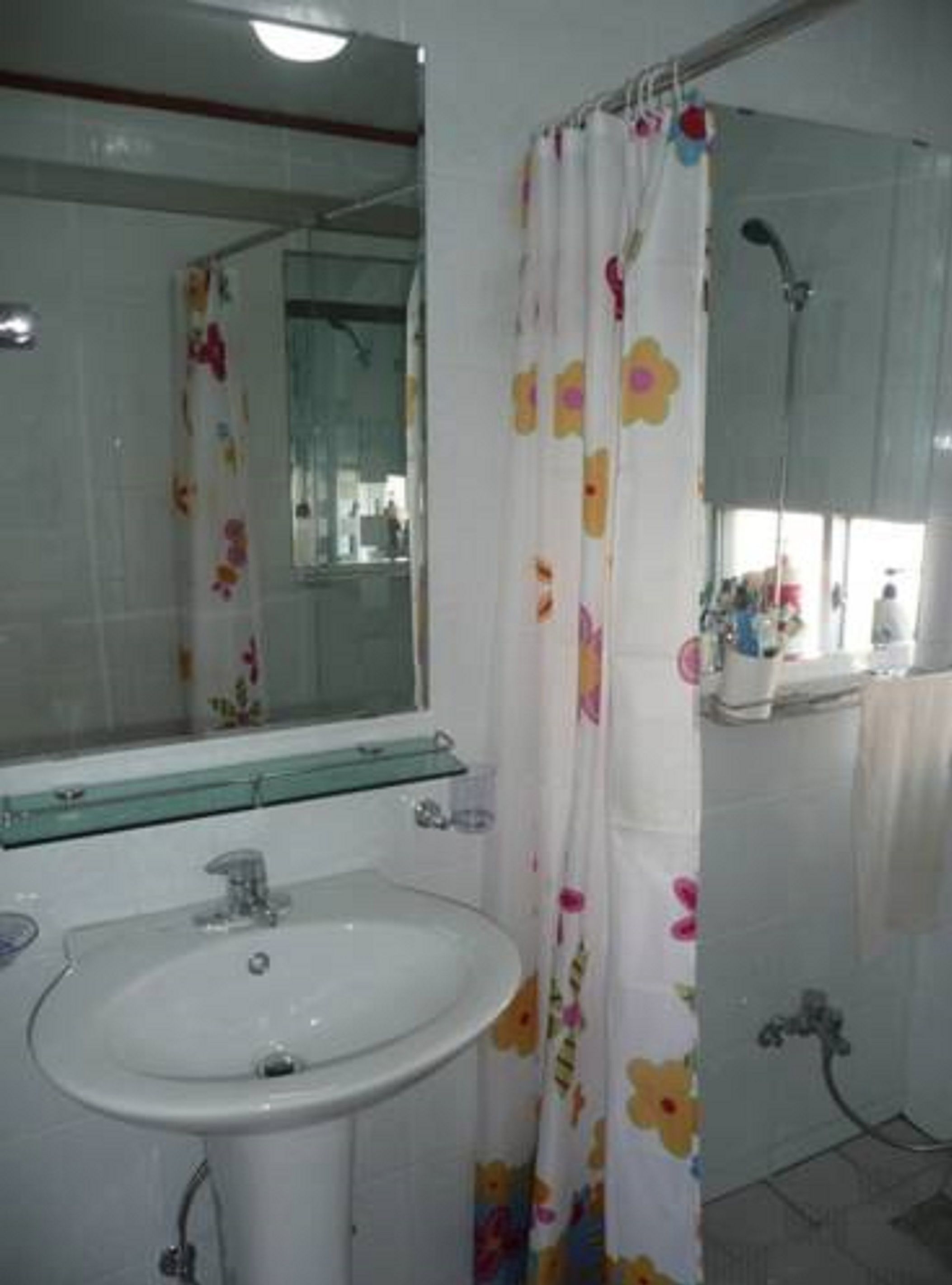 A bathroom with a white sink, a mirror, and a shower curtain with floral patterns.