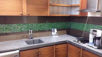 Una cocina con armarios de madera, un fregadero, una cafetera y un salpicadero de azulejos.