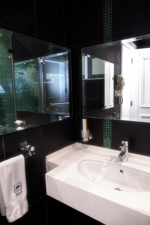 A modern bathroom with a large mirror, a white sink, and a towel hanging on the wall. - Aswar Hotel (Al Khobar)