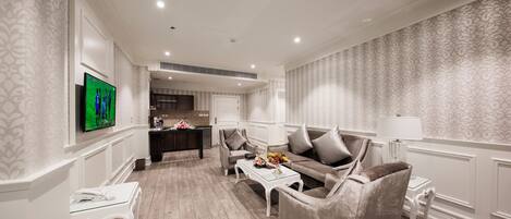A modern living room with a sofa, armchairs, a coffee table, and a TV.