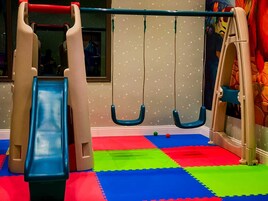 Zona de juegos con tobogán, columpios y estructura para escalar.