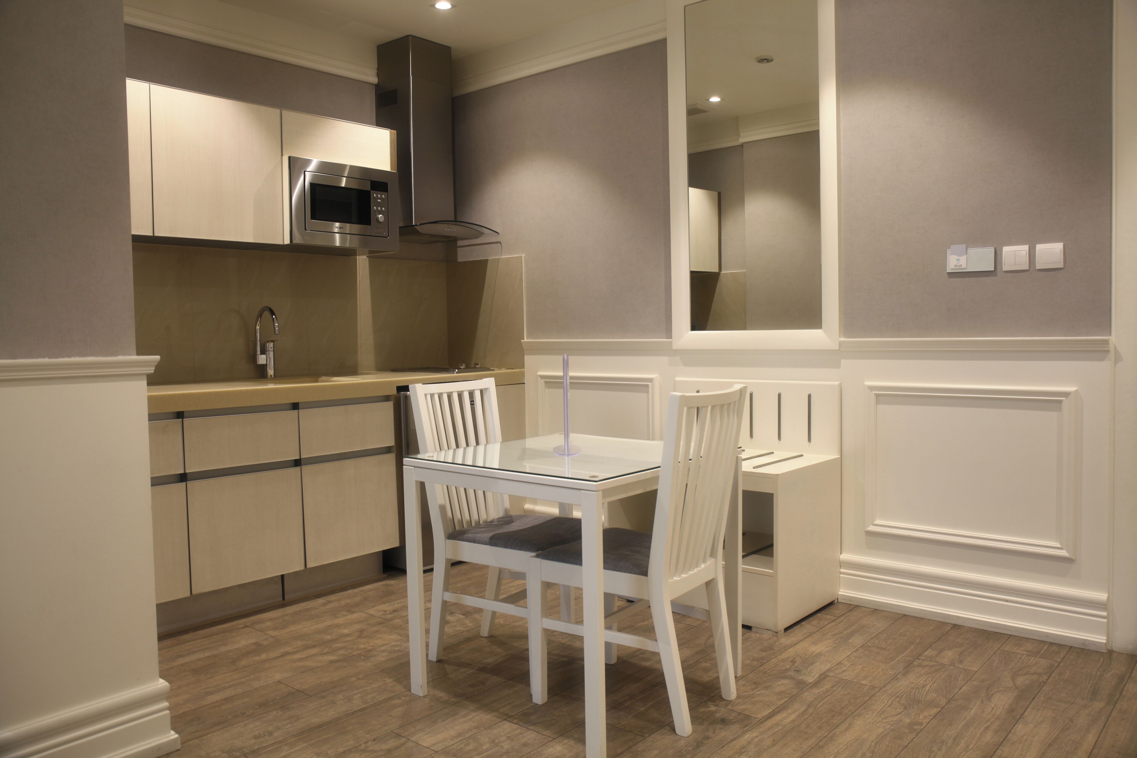 A modern kitchen with a built-in microwave, a stainless steel range hood, and a double sink.