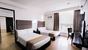 Habitación de hotel con dos camas, un escritorio, una silla y un televisor.