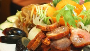 Una variedad de carnes y verduras en un plato, incluyendo lonchas de salchicha, champiñones y adornado con hierbas.
