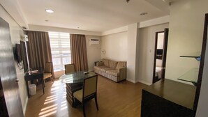 Una sala de estar moderna con una mesa de comedor de vidrio, un sofá y un televisor montado en la pared.