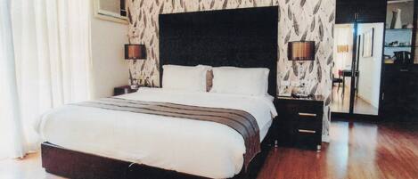 A hotel bedroom with a large bed, two bedside tables, a wardrobe, and a mirror.
