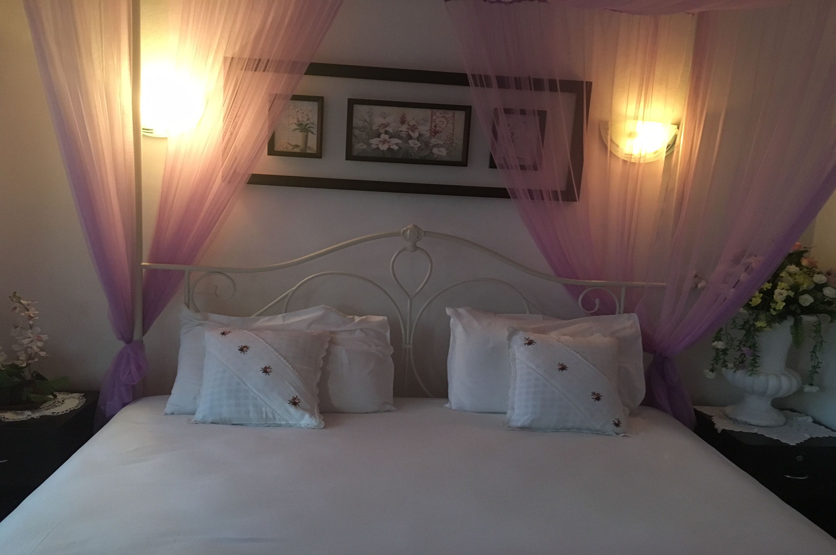 A bed with a canopy, two bedside tables, and wall-mounted lights.