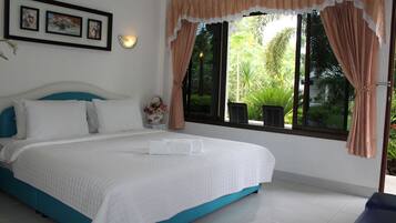 A bedroom with a bed, a nightstand, a window with curtains, and framed pictures on the wall.