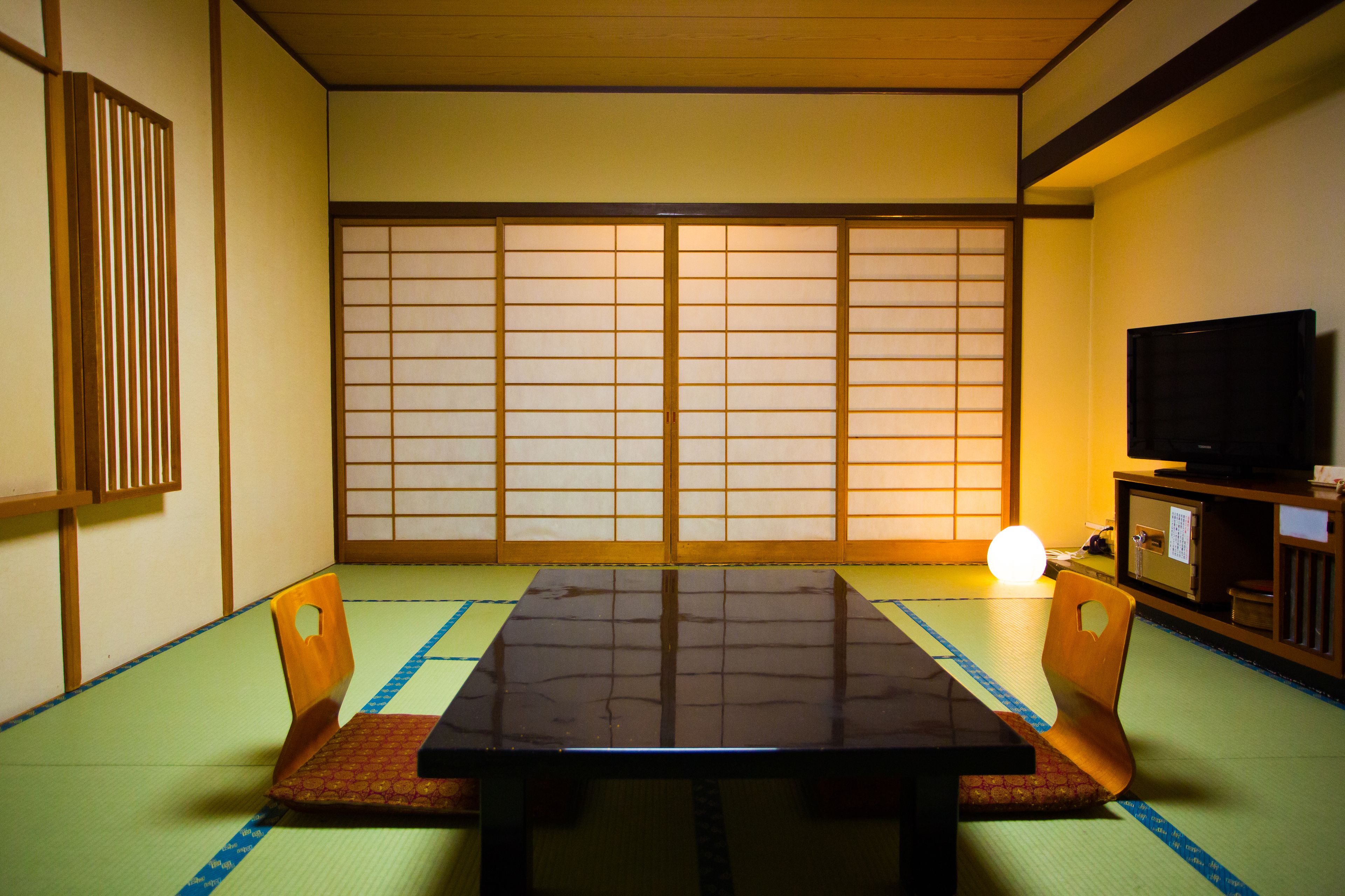 Una tradizionale stanza giapponese con pavimento in tatami, un tavolino e porte scorrevoli.