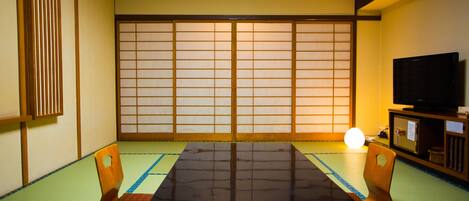 Una tradizionale stanza giapponese con pavimento in tatami, un tavolino e porte scorrevoli.
